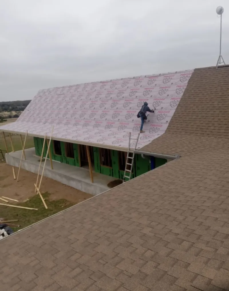 Worker preparing underlayment for a metal roof installation in Germantown
